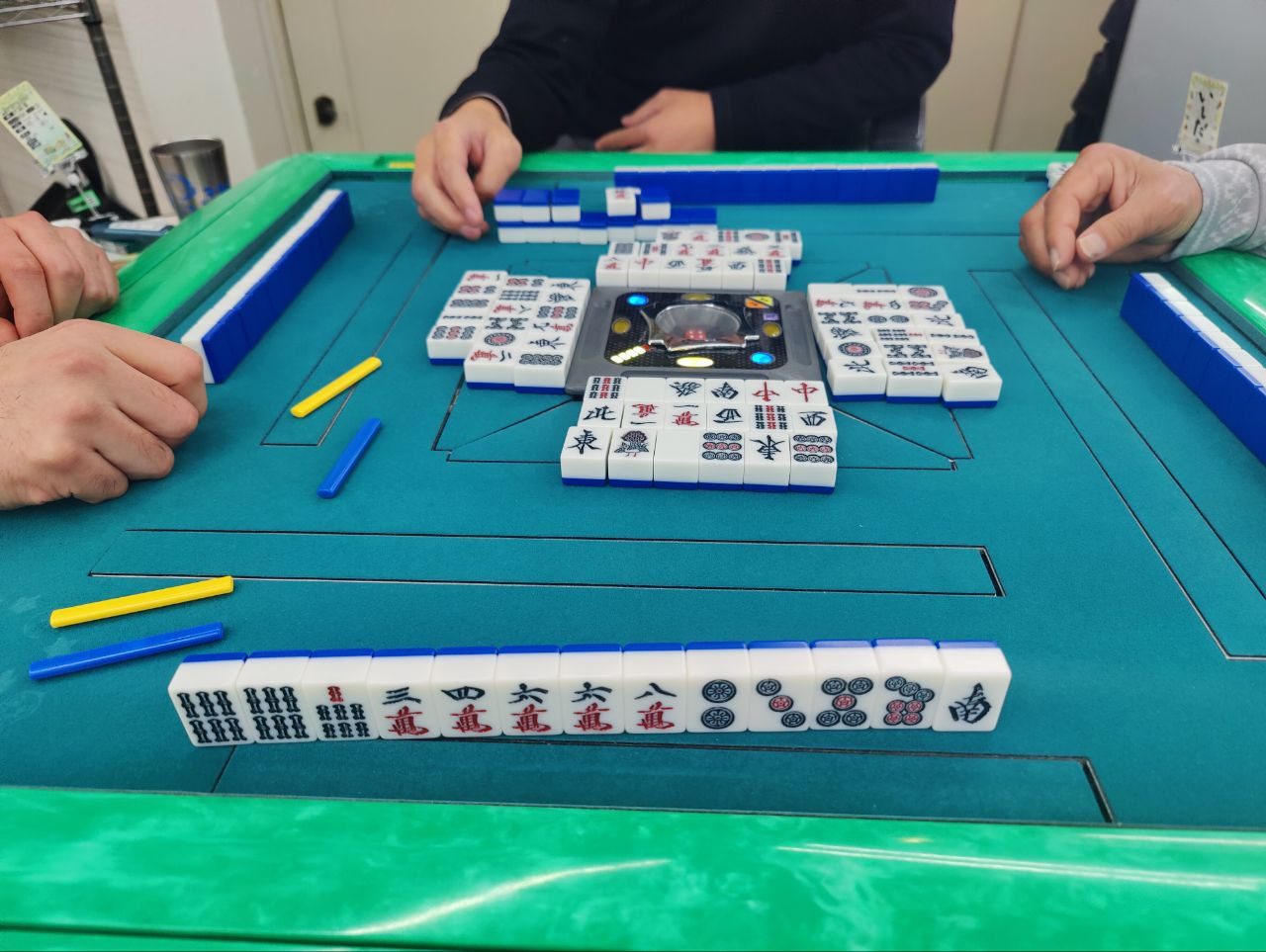 Mesa de Riichi durante una partida, con los muros, los descartes y los palos de apuesta
